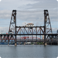 The Steel Bridge of Portland, Oregon is viewed from a distance as a light rail train goes over.