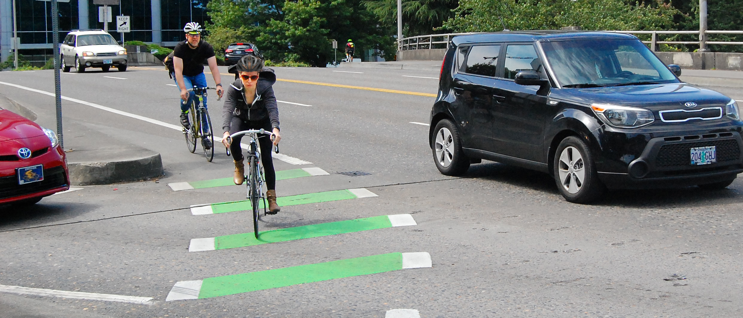 Bicyclists ride in a painted bike lane, defined by green stripes