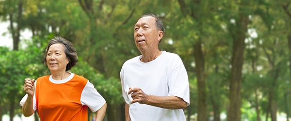 An older couple jogs through a park