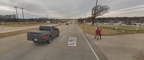 Pedestrians walk along a four-lane road with no sidewalk in Texas.