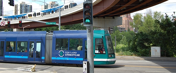 The Portland Streetcar and Portland MAX are visible, along with a green Bike Signal and a pedestrian walk button.