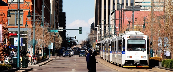 Pedestrians cross near a light rail amid mixed-use development