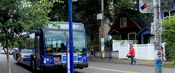 A bus coming up to a bus stop with a pedestrian nearby