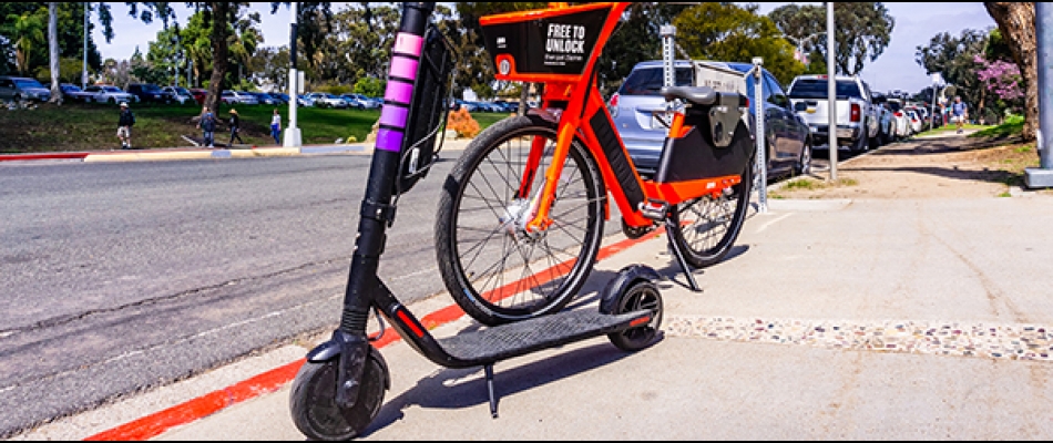 Escooter and bike parked on sidewalk